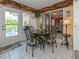 Relaxing dining area features a charming iron table set, wood paneled walls, and plenty of natural light at 4176 Summertree Rd, Venice, FL 34293
