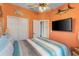 Cozy bedroom featuring orange walls, a queen-sized bed, and a mounted television at 4260 Wordsworth Way, Venice, FL 34293