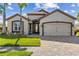 Charming home exterior featuring a brick driveway, manicured lawn, and a well-maintained two-car garage at 4260 Wordsworth Way, Venice, FL 34293