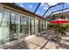 Covered lanai with a wooden deck, furniture, and a red umbrella overlooking tropical foliage at 4260 Wordsworth Way, Venice, FL 34293