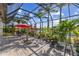 Screened patio with an outdoor dining area, beautiful plants, and a peaceful waterfront view at 4260 Wordsworth Way, Venice, FL 34293