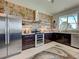 Well-lit kitchen with modern stainless steel appliances, brick accent wall and island sink at 48 Lark Dr, Placida, FL 33946