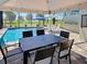 Poolside patio with brick pavers, screen enclosure, patio umbrellas, chairs, table, and pool at 48 Lark Dr, Placida, FL 33946