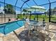 Outdoor pool, patio furniture, screen enclosure, tropical landscaping, umbrellas, and stone pavers at 48 Lark Dr, Placida, FL 33946