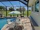 Relaxing poolside setup with a table, chairs, umbrella, and scenic backyard view at 48 Lark Dr, Placida, FL 33946