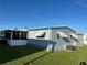 The rear exterior featuring blue siding, a screened in porch, and lush lawn at 529 Cervina S Dr, Venice, FL 34285