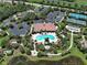 An aerial view captures the community clubhouse, swimming pool, tennis courts, and lush green surroundings at 5832 Semolino St, Nokomis, FL 34275