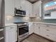 Kitchen featuring stainless steel oven and microwave, plenty of white cabinets, light countertops and light gray subway tile at 5832 Semolino St, Nokomis, FL 34275