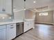 Open concept kitchen with stainless steel dishwasher, white cabinets, granite countertops, and light gray subway tile backsplash at 5832 Semolino St, Nokomis, FL 34275