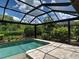 A screened-in pool with travertine tile patio and lush tropical landscaping provides a tranquil retreat at 5832 Semolino St, Nokomis, FL 34275