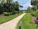 Scenic brick walking path winding through lush landscaping with tropical palm trees and a tranquil lake view at 5832 Semolino St, Nokomis, FL 34275