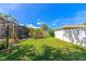 A beautiful, well-manicured backyard with lush green grass, a white fence, and a screened-in patio at 6964 Glacier Ave, North Port, FL 34291