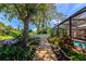 Backyard wooden path leading to a screened-in pool area with lush landscaping and a private, fenced yard at 6964 Glacier Ave, North Port, FL 34291