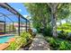 A lush backyard with a wooden path, vibrant plants, and a screened-in pool area, creating a private oasis at 6964 Glacier Ave, North Port, FL 34291