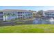 Three-story condo building surrounded by lush green lawns and a serene pond at 700 Gardens Edge Dr # 722, Venice, FL 34285
