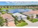 Aerial view of a bright, lakefront home showcasing a white tile roof and lush landscaping in a desirable community at 809 Derbyshire Dr, Venice, FL 34285