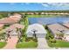 Lakefront home with a white tile roof, paver driveway, and mature landscaping, offering picturesque community views at 809 Derbyshire Dr, Venice, FL 34285