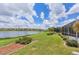 Spacious backyard with a serene lake view, lush lawn, and mature landscaping at 809 Derbyshire Dr, Venice, FL 34285