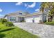 Stunning single-story home featuring a meticulously maintained lawn, paver driveway, and three-car garage at 8245 Grande Shores Dr, Sarasota, FL 34240