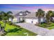 Beautiful gray home featuring a three-car garage, lush landscaping, and a paver driveway at 8245 Grande Shores Dr, Sarasota, FL 34240