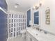 Bright bathroom featuring a shower with a blue and white curtain, a marble vanity and charming decorations at 841 Waterside Dr # 202, Venice, FL 34285