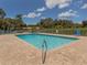 Community pool with brick paver deck, clear blue water, surrounded by a white fence, with seating for residents at 841 Waterside Dr # 202, Venice, FL 34285