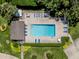 Aerial view of a well-maintained community pool with lounge chairs, lush landscaping, and paved pool deck at 841 Waterside Dr # 202, Venice, FL 34285