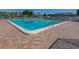 Sparkling community pool surrounded by a brick patio and comfortable lounge chairs at 841 Waterside Dr # 202, Venice, FL 34285