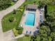 Aerial view of a community pool with ample seating, lush landscaping, and a nearby parking area at 841 Waterside Dr # 202, Venice, FL 34285