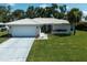 Inviting single-story home with a pristine lawn, attached garage, light-colored roof, and a lovely, bright blue front door at 903 E Shannon Ct, Venice, FL 34293