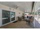 A covered outdoor patio featuring tile flooring, ceiling fans, and comfortable seating area with sliding glass doors to the pool at 903 E Shannon Ct, Venice, FL 34293