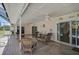 A covered outdoor patio featuring tile flooring, ceiling fans, and comfortable seating area with sliding glass doors to the pool at 903 E Shannon Ct, Venice, FL 34293