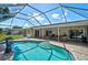 Screen enclosed in-ground pool with brick paver patio and view of the covered outdoor patio with seating area at 903 E Shannon Ct, Venice, FL 34293