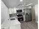 Modern kitchen featuring stainless steel appliances, white cabinets, quartz countertops, and gray backsplash at 9110 Lunar Ln, Port Richey, FL 34668