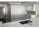 Modern kitchen featuring stainless steel appliances, white cabinets, quartz countertops, and gray backsplash at 9110 Lunar Ln, Port Richey, FL 34668