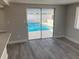 Light filled living room with gray wood grain flooring and sliding glass doors leading to outdoor pool and patio at 9110 Lunar Ln, Port Richey, FL 34668