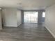 Bright living room with updated gray floors, neutral walls, and sliding glass doors to the pool at 9110 Lunar Ln, Port Richey, FL 34668