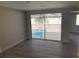 Bright living room with updated gray floors, neutral walls, and sliding glass doors overlooking pool at 9110 Lunar Ln, Port Richey, FL 34668