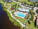 Aerial view of community amenities including a pool, playground, tennis courts, and lush green spaces along the water at 935 Tidewater Shores # 721, Bradenton, FL 34208