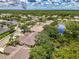 Aerial view of neighborhood featuring homes, lakes, lush landscaping, and mature trees on a sunny day at 9361 Carnaby Dr, Venice, FL 34293