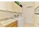 Well-organized laundry room with white cabinets, countertop space, and washer and dryer at 9361 Carnaby Dr, Venice, FL 34293