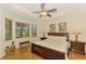 Cozy main bedroom featuring a tray ceiling, bay window, hardwood floors, and decorative lamps at 9361 Carnaby Dr, Venice, FL 34293