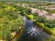 Aerial view of a tranquil lake with fountain surrounded by lush green trees at 9361 Carnaby Dr, Venice, FL 34293
