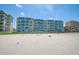 Condominium building exterior with beach access, blue windows, and lush vegetation at 950 Tarpon Center Dr # 305, Venice, FL 34285