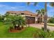 Inviting home featuring a tile roof, brown garage doors, palm trees, and lush landscaping at 121 Colebrook Ct, Venice, FL 34292
