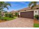 Beautiful home with a brown garage door, paver driveway, lush lawn, and tropical plants at 121 Colebrook Ct, Venice, FL 34292