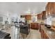 Open kitchen with granite countertops, wood cabinetry, and an island with bar seating at 1222 Pinebrook Way, Venice, FL 34285