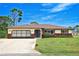 Charming single-story home featuring a two-car garage, brick accents, mature trees, and a well-manicured lawn at 1290 Leeward Rd, Venice, FL 34293