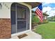 Welcoming front porch with a screen door, American flag, and beautifully landscaped yard, offering great curb appeal at 1290 Leeward Rd, Venice, FL 34293