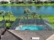 Aerial view of a screened pool with a lake view surrounded by lush landscaping at 13862 Miranese St, Venice, FL 34293